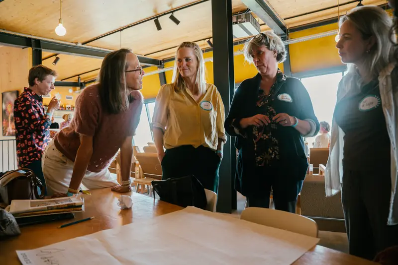 Deelnemers in gesprek rond een tafel vol papier